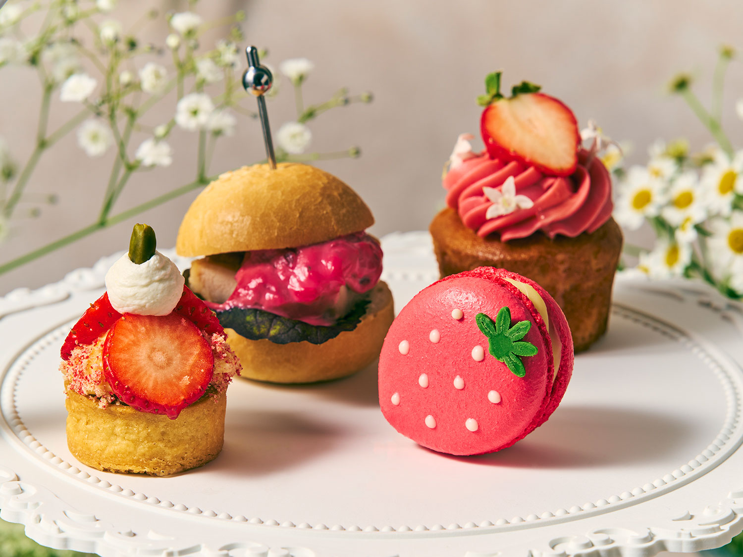 「苺とピスタチオのハーブ香るタルト」（左前）、「ハーブチキンサンド　木苺のソース」（左奥）、「苺仕立てのマカロン　レモングラスのホワイトショコラ」（右前）、「苺づくしのカップケーキ」（右奥）